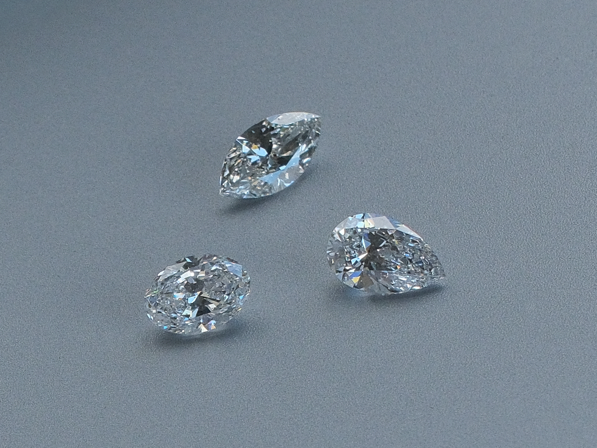 Three diamonds in marquise, oval and pear cuts on a grey surface