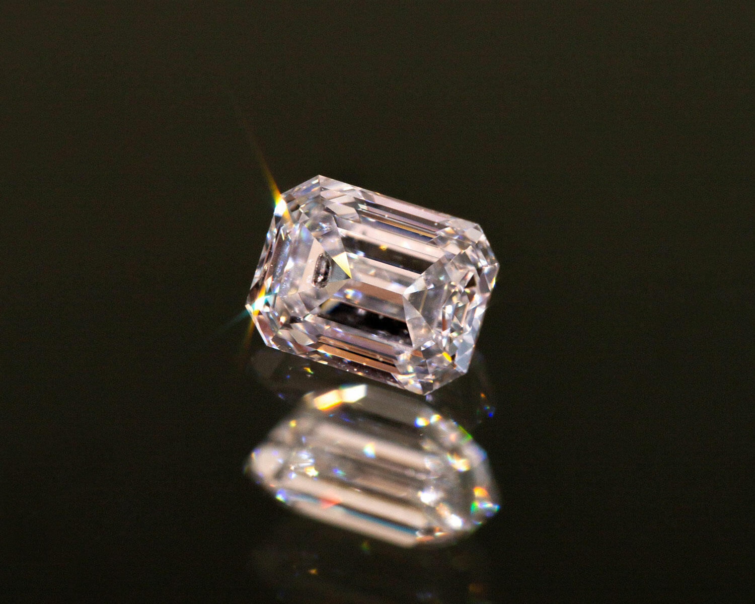 Natural white diamond on a black background reflecting onto the surface below