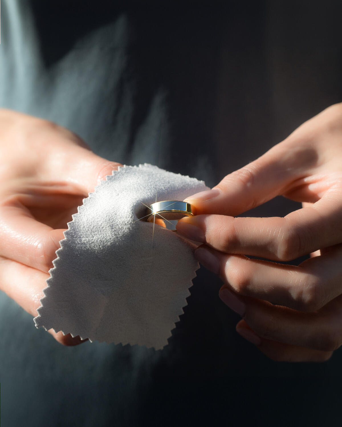 Women cleaning engagement ring with a polishing cloth