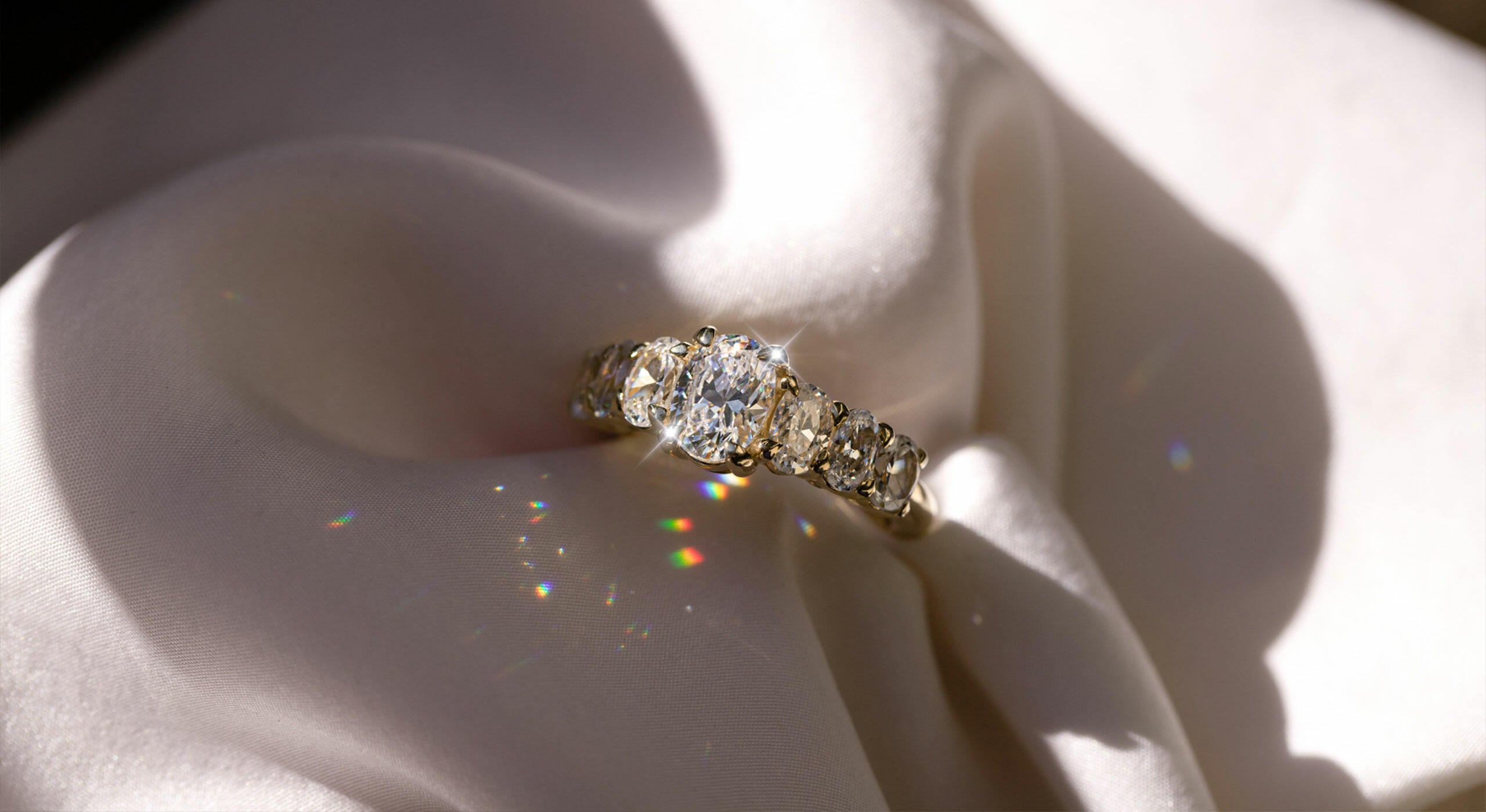 Image of an engagement ring with an oval centre stone and 3 side stones on each side scaling down