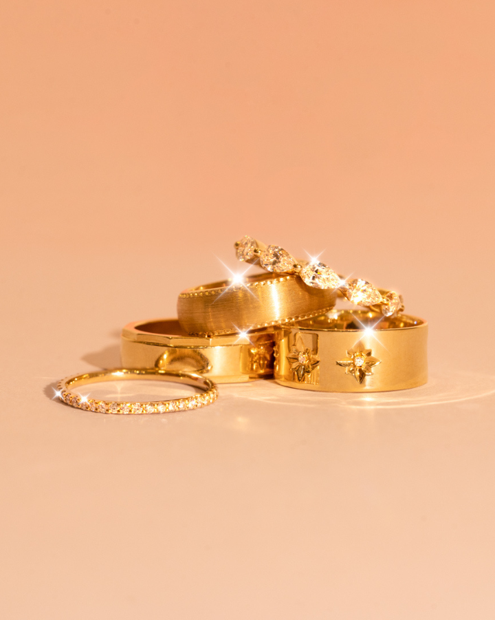 Five wedding bands stacked on one another including plain and diamond band styles