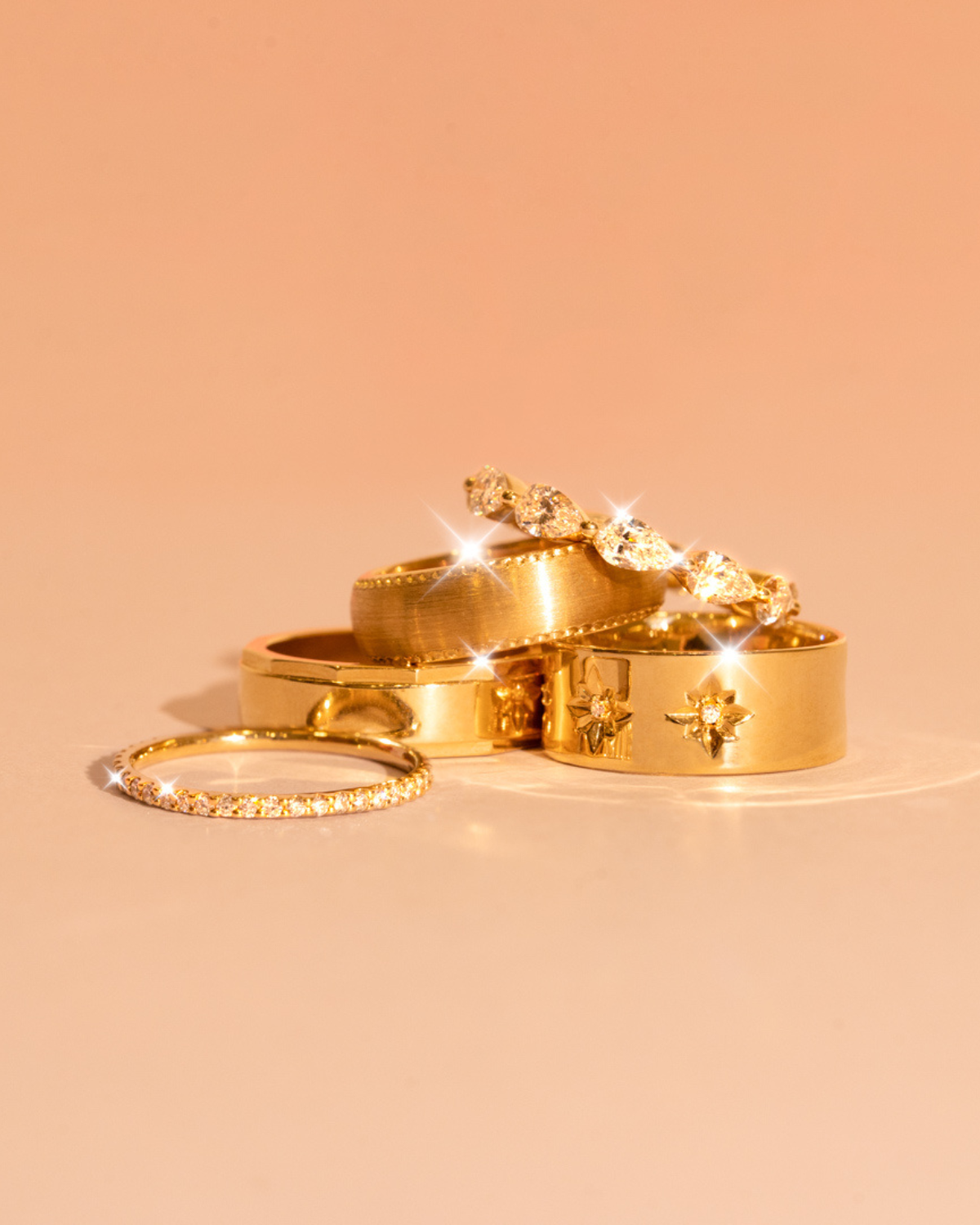 Five wedding bands stacked on one another including plain and diamond band styles